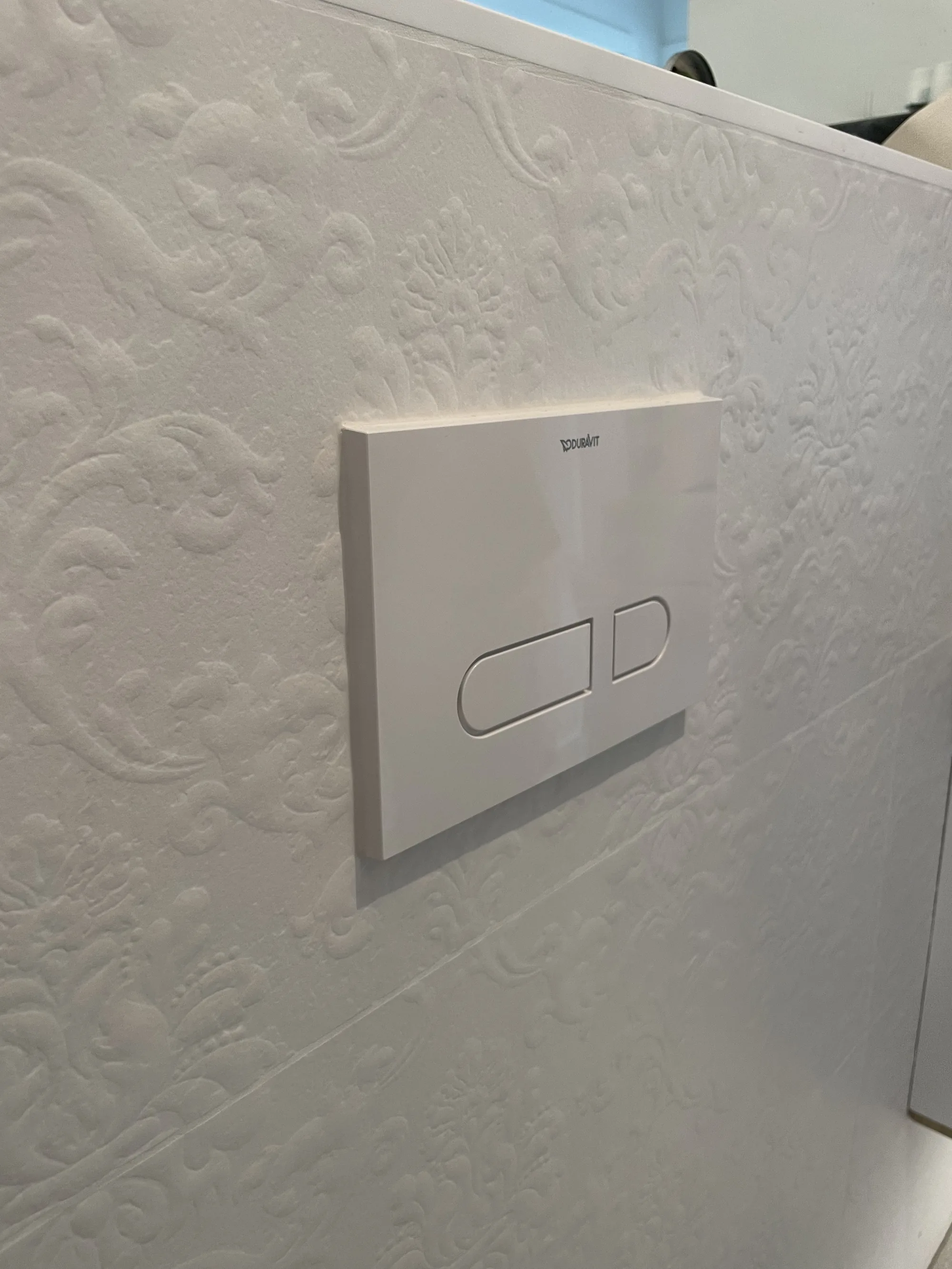Weiße Strukturfliesen mit WC-Drückerplatte