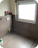 Badezimmer mit grauen Fliesen und Fenster